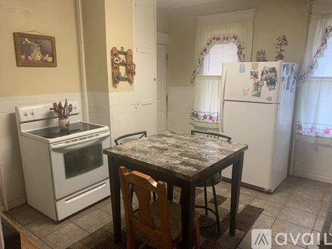 A kitchen with a table and chairs in front of a fridge.
