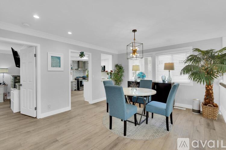 A dining room with a table set for four and a potted plant.