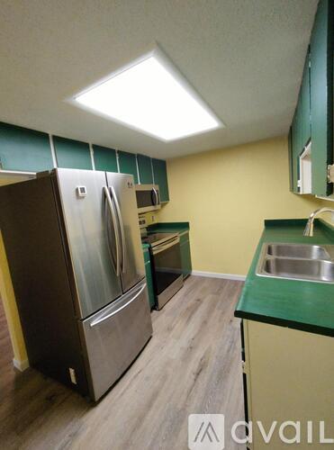 A kitchen with a refrigerator, microwave, and sink.