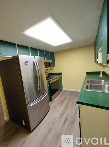 A kitchen with a refrigerator, microwave, and sink.