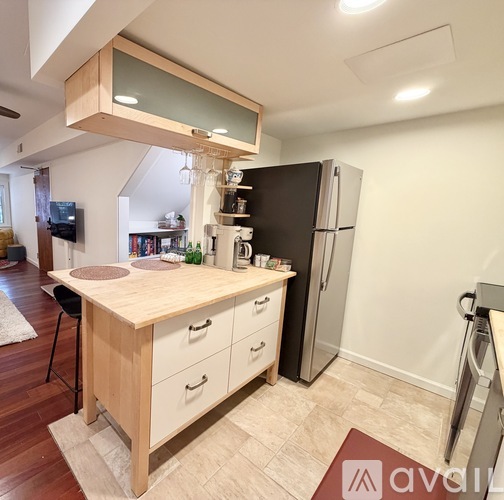 A kitchen with a wooden island and a black refrigerator.