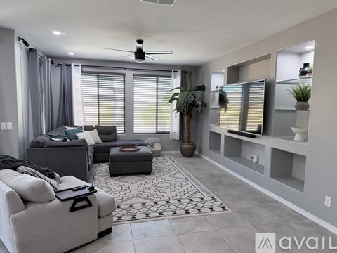 A living room with a grey sofa, a coffee table, and a ceiling fan.