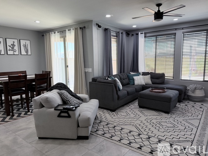 A living room with a grey sofa set and a patterned rug.