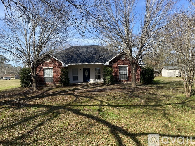 A house with a red brick exterior and a white door is surrounded by bare trees.