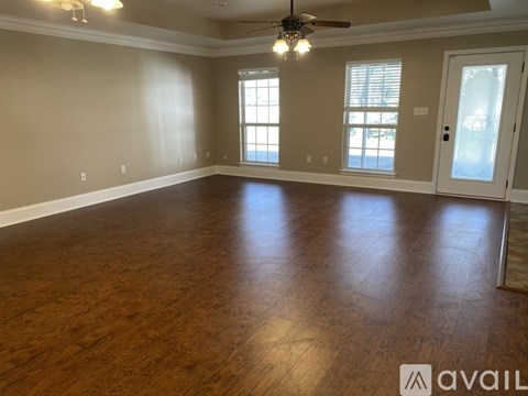 A spacious room with wooden flooring and a ceiling fan.
