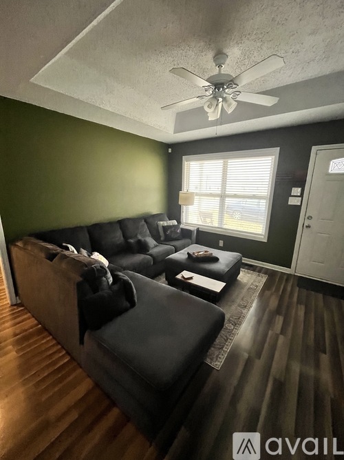 A living room with a black couch and a ceiling fan.