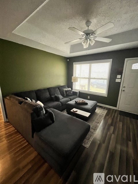 A living room with a black couch and a ceiling fan.
