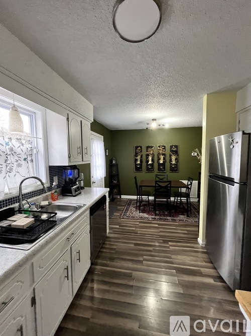A kitchen with a refrigerator, sink, and dining table.