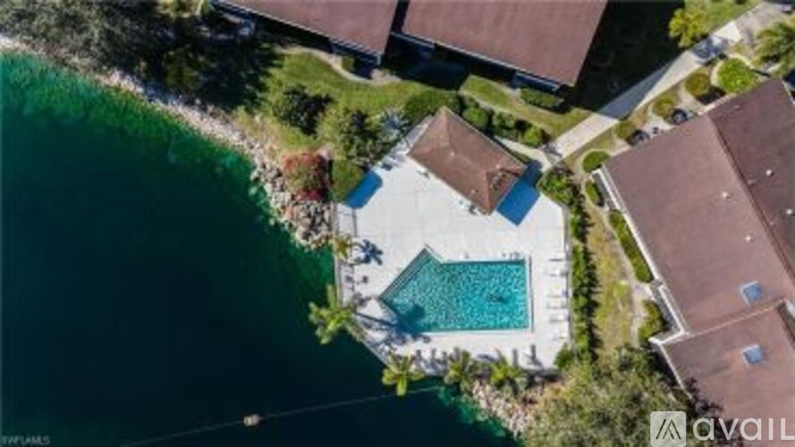 An aerial view of a house with a swimming pool next to a body of water.