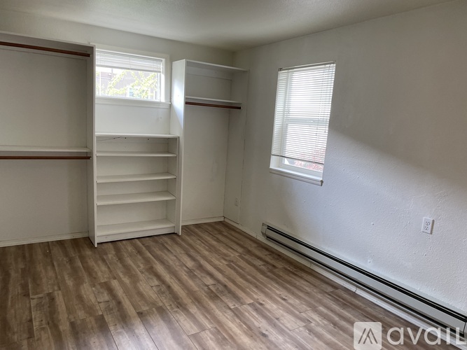 A room with white shelves and wooden flooring.