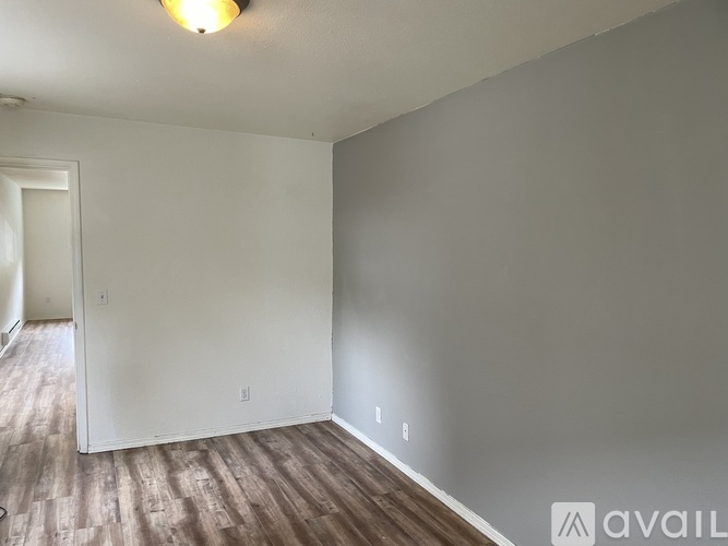 A room with wooden flooring and white walls.
