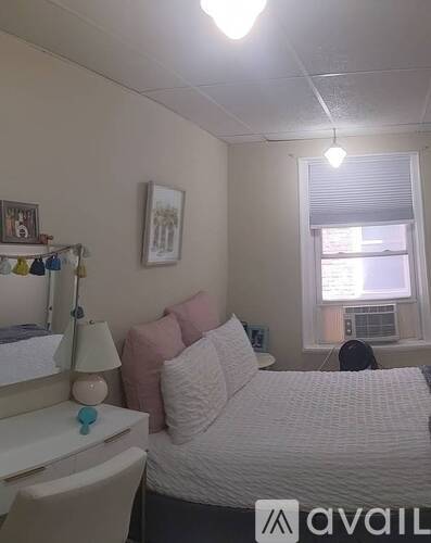 A bedroom with a bed, desk, and window.