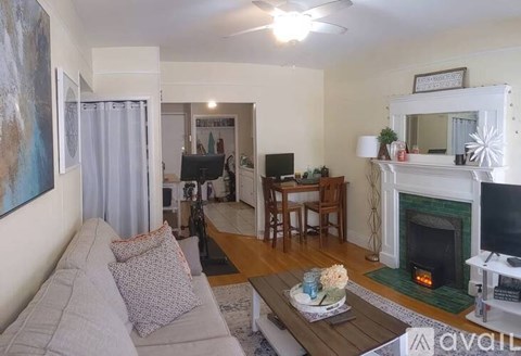 A living room with a grey couch, a coffee table, a fireplace, and a painting on the wall.