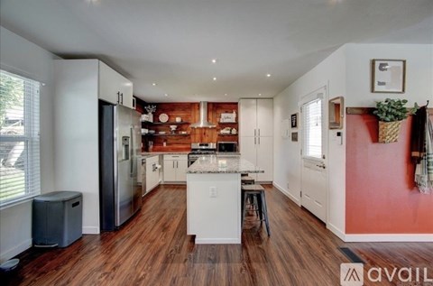 A kitchen with white cabinets and a wooden floor.