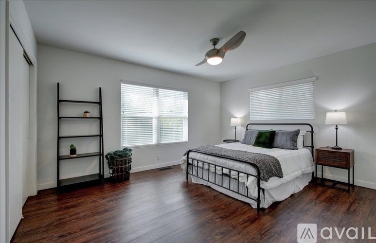 A bedroom with a bed, a shelf, and a ceiling fan.
