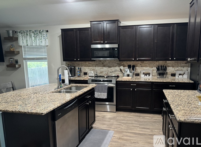 A kitchen with granite countertops and dark wood cabinets.