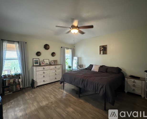 A bedroom with a bed, dresser, and ceiling fan.