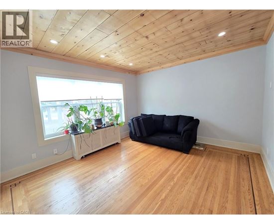 A living room with a black couch and wooden floors.