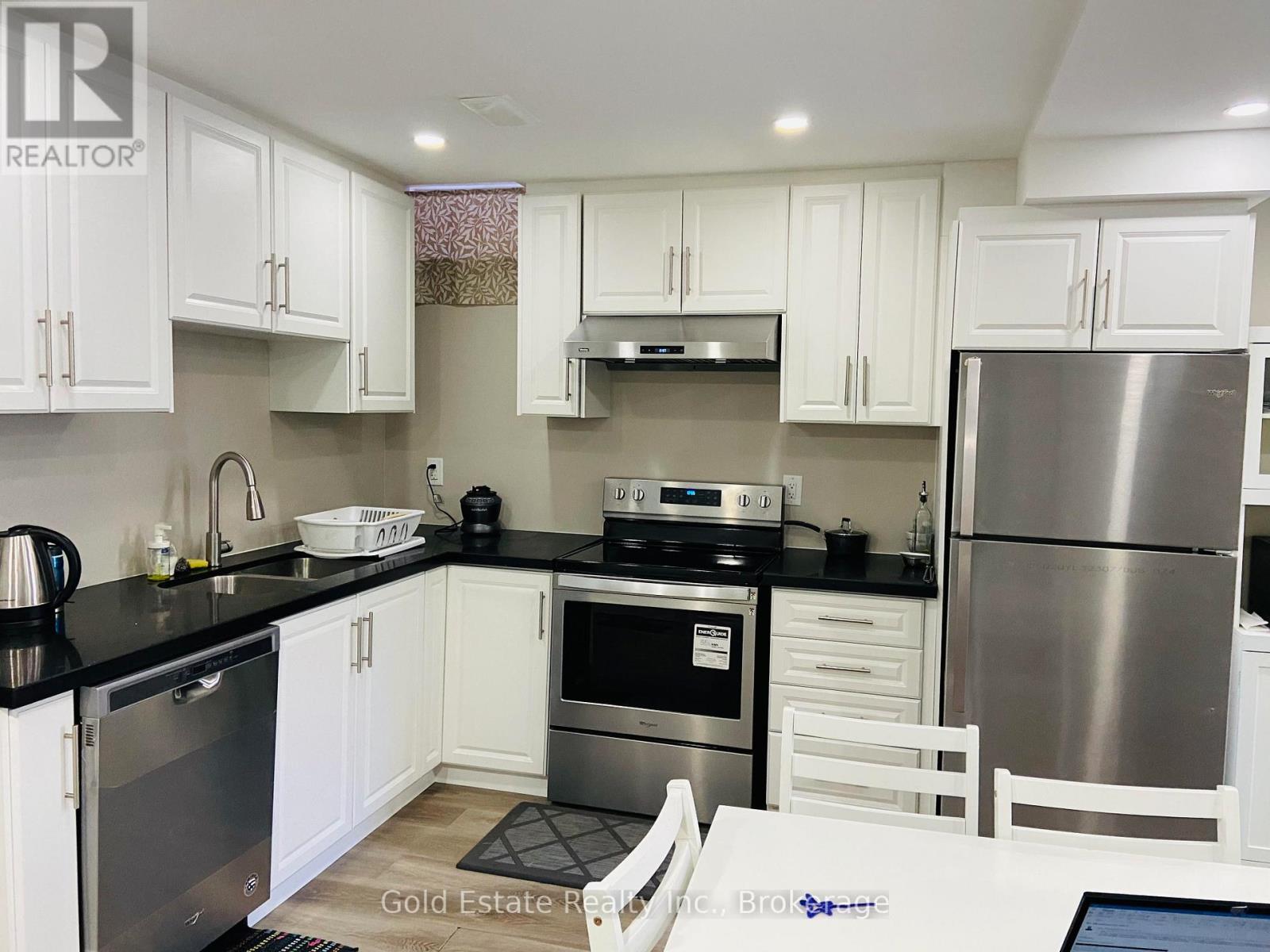A kitchen with white cabinets and black countertops.