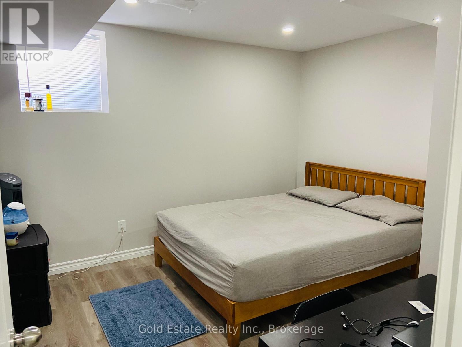 A bedroom with a bed, nightstand, and a window with blinds.