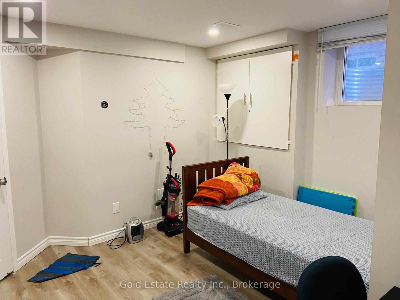 A bedroom with a bed, a blue chair, and a wall with a tree cutout.