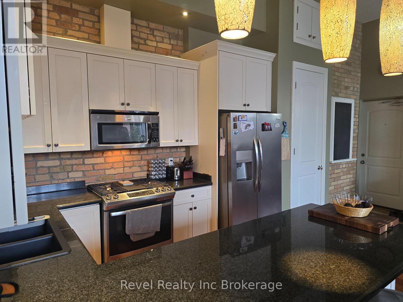A kitchen with a black counter top and stainless steel appliances.