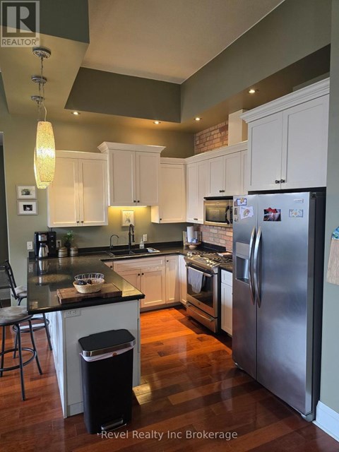 A kitchen with a black counter top and stainless steel appliances.