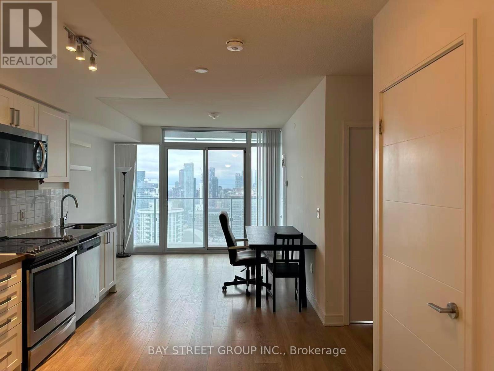 A kitchen with a dining table and chairs in front of a window with a view of the city.