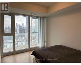 A bedroom with a large bed and a view of the city through the windows.