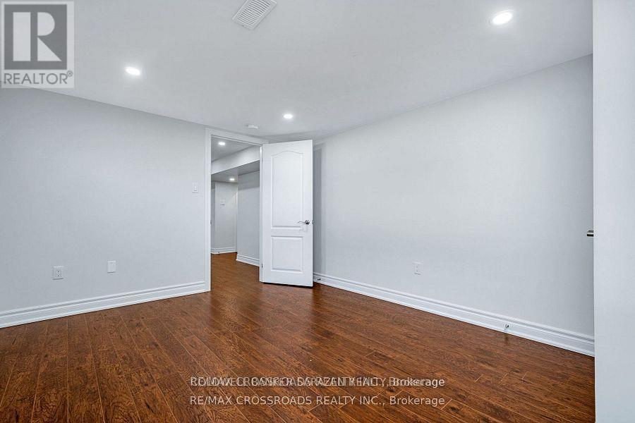 A spacious room with wooden floors and white walls, ready for staging.