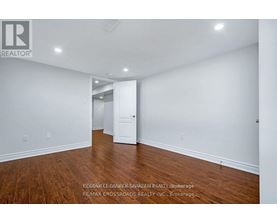 A spacious room with wooden floors and white walls, ready for staging.