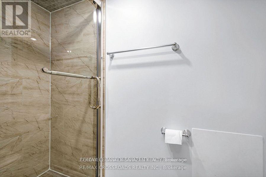 A bathroom with a glass shower door and a towel rack.