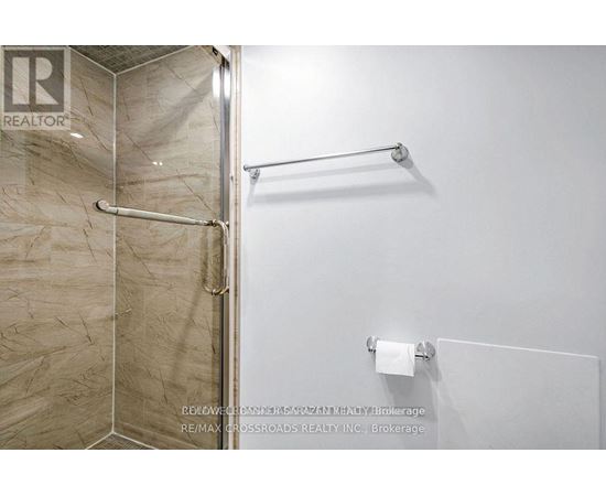 A bathroom with a glass shower door and a towel rack.