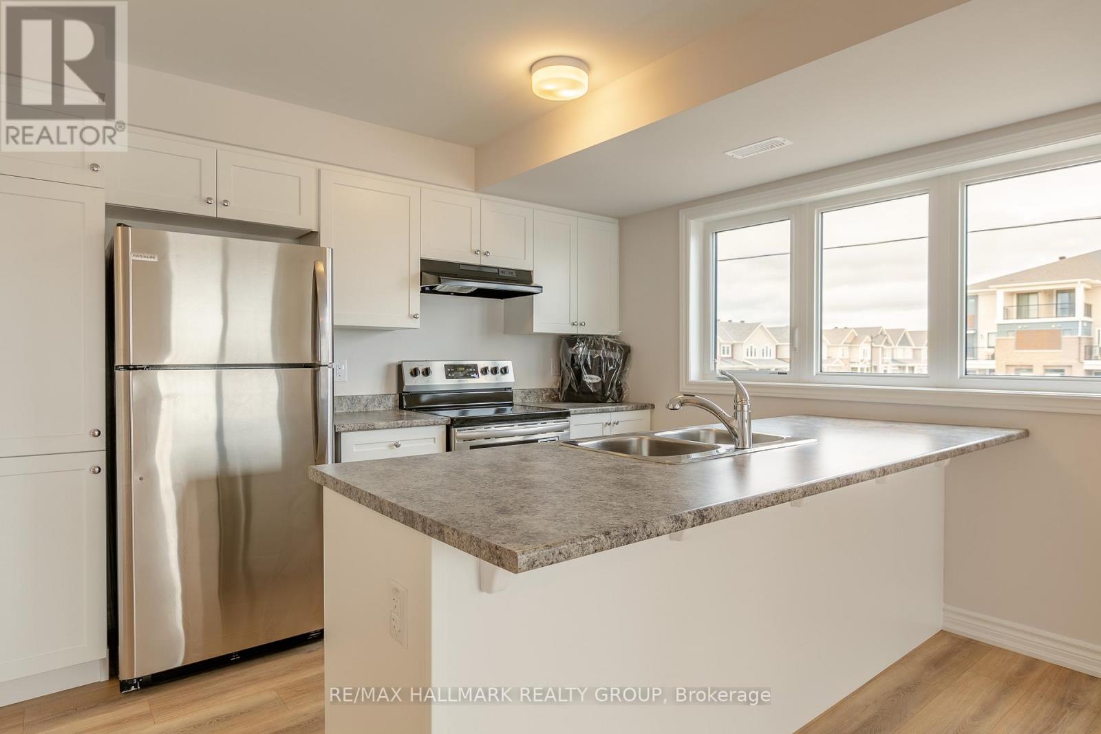 A kitchen with a stainless steel refrigerator and a marble countertop.