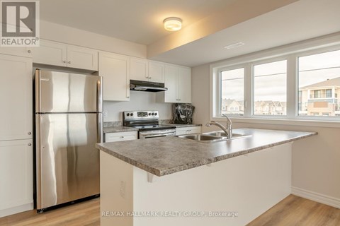 A kitchen with a stainless steel refrigerator and a marble countertop.
