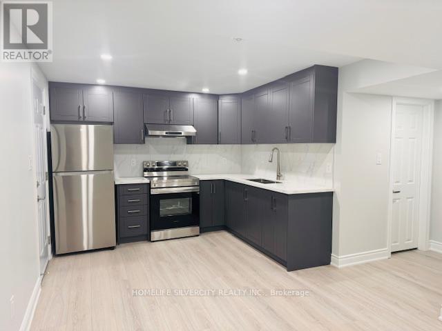 A kitchen with a refrigerator, oven, and sink.