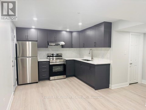 A kitchen with a refrigerator, oven, and sink.