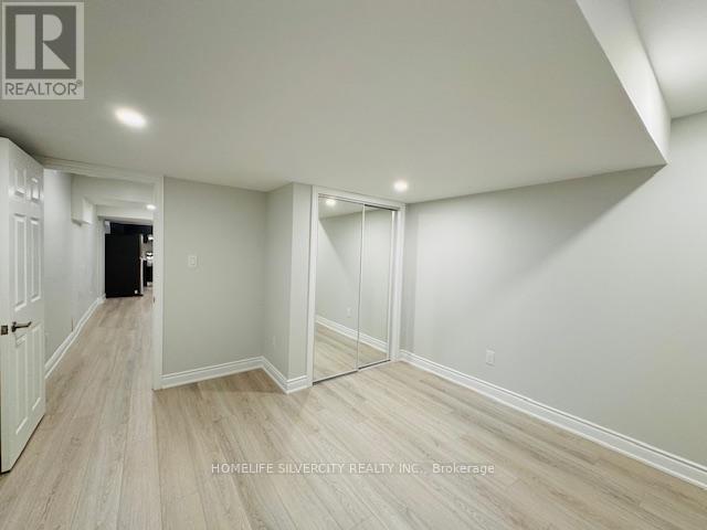 A spacious room with white walls and wooden flooring.
