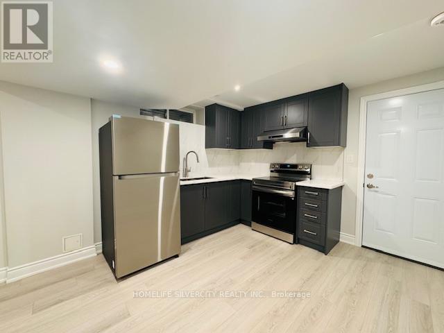 A kitchen with a refrigerator, sink, and cabinets.