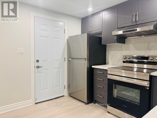 A kitchen with a white door and a black refrigerator.