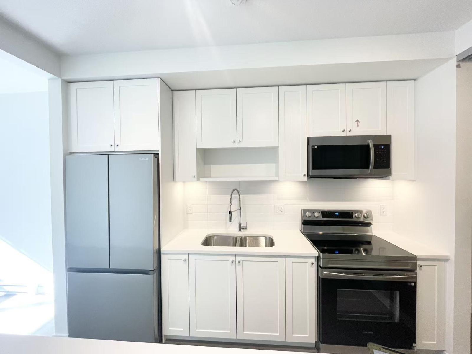 A kitchen with white cabinets and a black stove top oven.