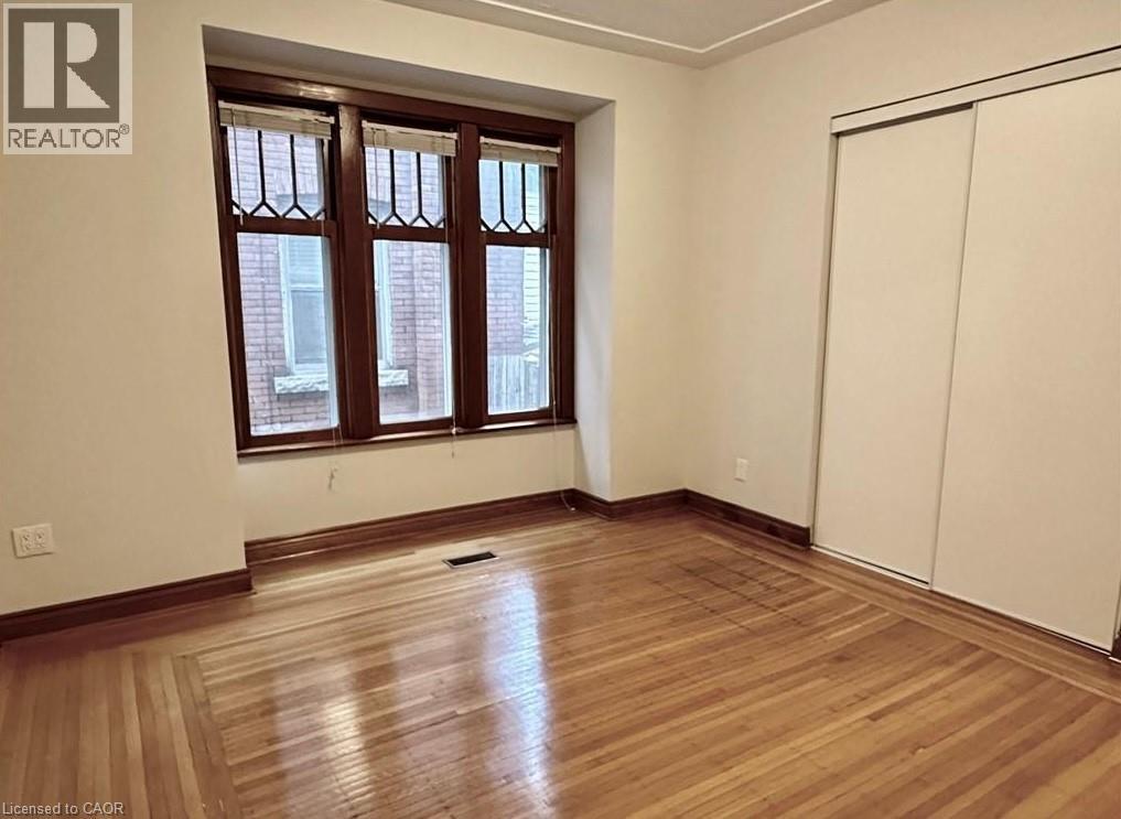 A room with wooden flooring and a window with a view of a building.