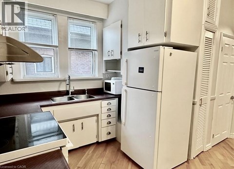 A white refrigerator is in a kitchen with white cabinets.