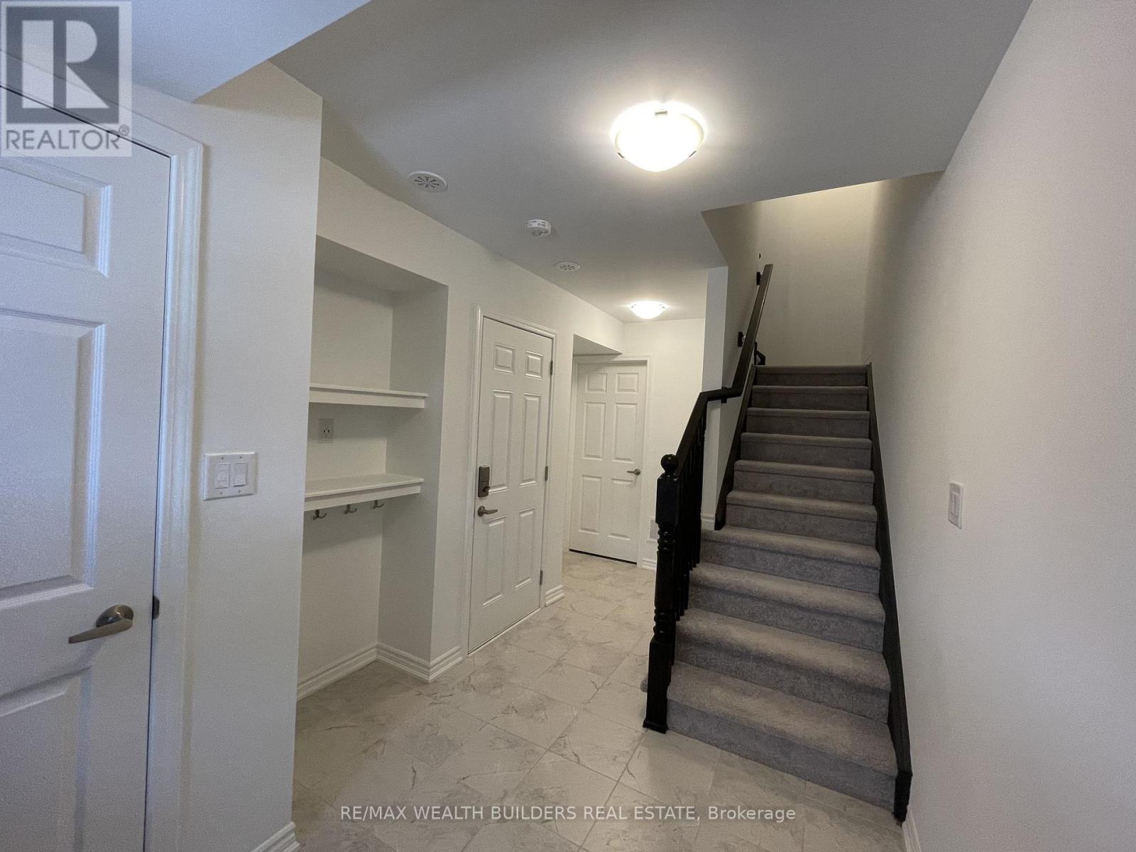 A hallway with a staircase and a white door.