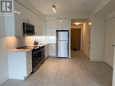 A kitchen with white cabinets and a refrigerator.
