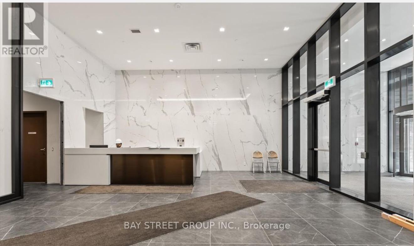 A reception area with a marble wall and a desk with chairs.