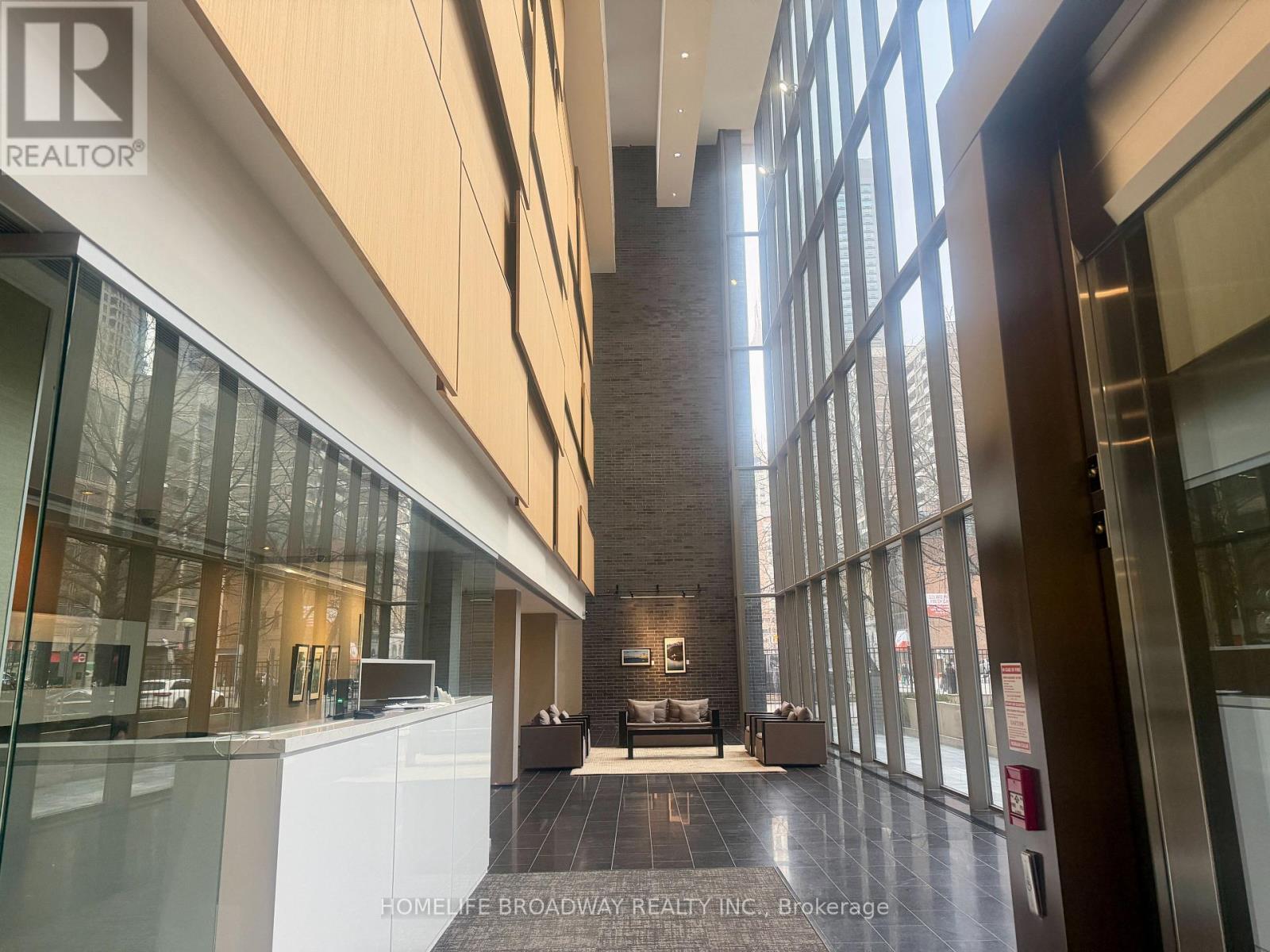 A modern interior space with a long hallway and glass walls on one side.