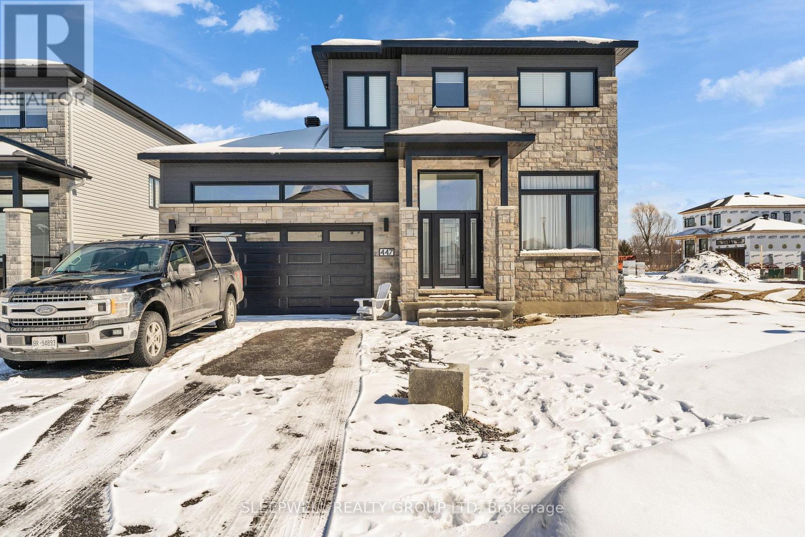 A modern house with a garage and a truck parked in front.