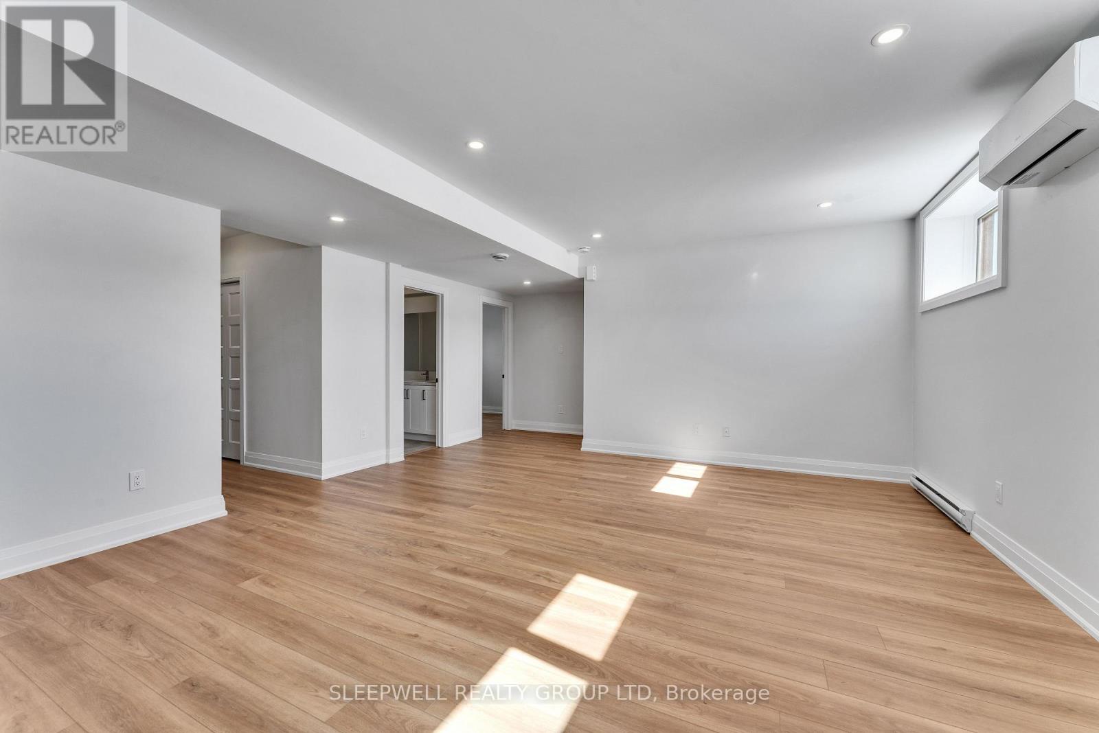 A spacious room with wooden flooring and white walls.