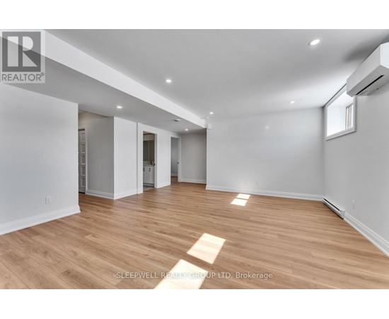 A spacious room with wooden flooring and white walls.